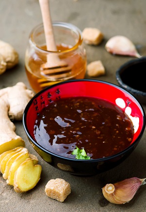 Ein Schälchen mit Teriyaki-Sauce, darum herum sind die notwendigen Zutaten stilvoll angeordnet.
